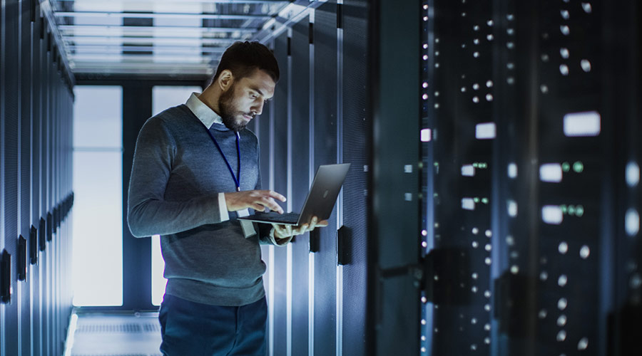 Mann mit Notebook im Serverraum